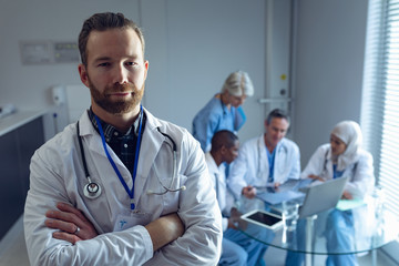 Male doctor standing with arm crossed at hospital