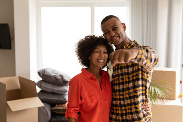 Happy couple holding new house keys in living room at home