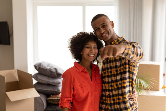 Happy Couple Holding New House Keys In Living Room At Home