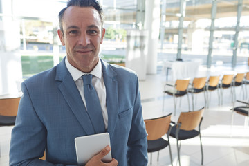 Caucasian businessman standing in conference room holding digital tablet