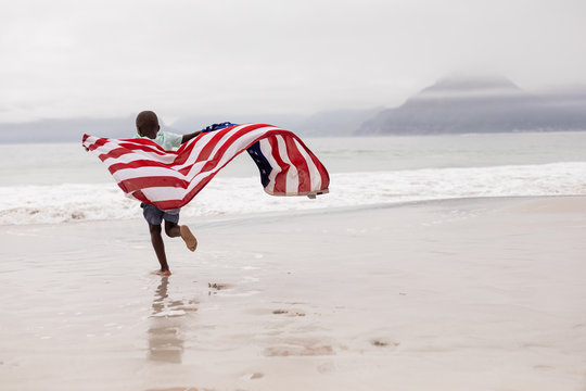 Boy running with American flag on the beach