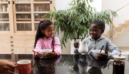 Siblings having food on a table in kitchen at home