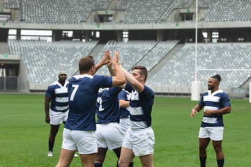 Diverse male rugby players celebrating goal in stadium