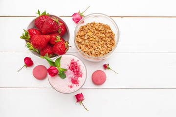 Healthy breakfast with yoghurt, granola and strawberries on white wooden background top view