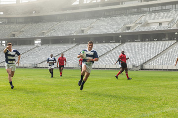 Group of diverse male rugby players playing rugby in stadium