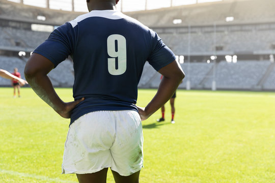 Male rugby player standing with hands on hip in the stadium