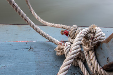 Boat rope tied to a wooden post on a floating boat railing, close up.