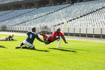 Male rugby players playing rugby match in stadium