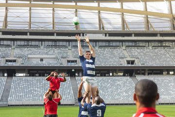Male rugby players playing rugby match in stadium