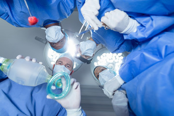 Surgeons standing with oxygen mask in operation theater at hospital