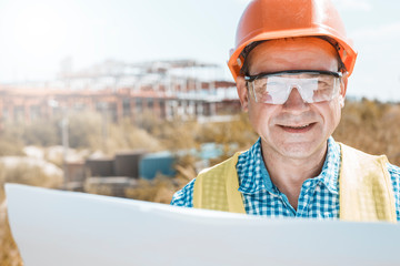 Male builder, architect or engineer in a helmet and glasses on a construction site. 