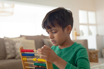 Boy learning mathematics with abacus in a comfortable home