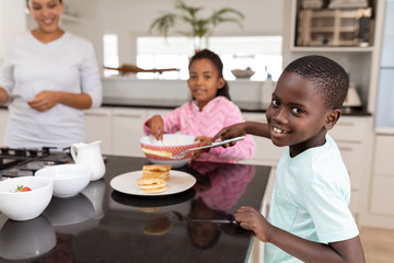 Obraz na płótnie Canvas Mother and children preparing food on a worktop in kitchen