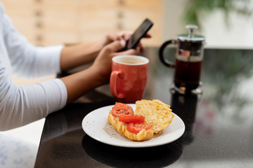 Woman using mobile phone on a table at kitchen