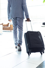 Young African-american male executive walking with suitcase