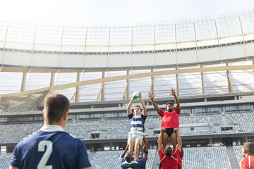 Male rugby players playing rugby match in stadium