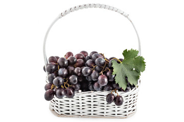 Fresh ripe red grapes in white wooden basket isolated on a white