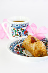 Eastern Turkish traditional sweet baklava on colorful plate and a cup of coffee