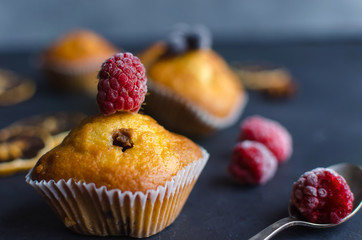 Sweet muffins with berries on dark textured background.
