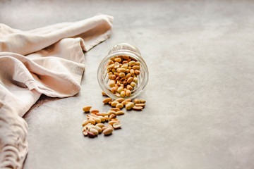 Roasted peanuts in a glass on a gray background. Healthy lifestyle and fast snack concept. Copy space for text.