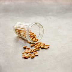 Roasted peanuts in a glass on a gray background.