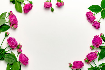 Flat lay flowers composition. Frame made of bright pink rose flowers on light gray background top view copy space. Greeting card for Birthday, Womens or Mothers Day, Valentine's Day, wedding