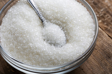 Bowl of sugar with spoon on wooden table