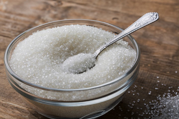 Bowl of sugar with spoon on wooden table