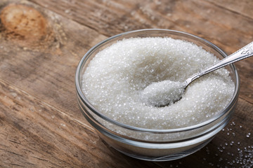 Bowl of sugar with spoon on wooden table