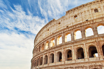 Fototapeta premium View of the top of amphitheater of Colosseum against blue sky with wispy clouds