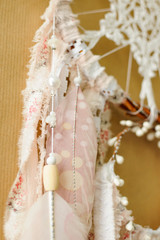 Closeup details handmade dreamcatcher with crochet doily snowflake and painted feathers on craft paper background