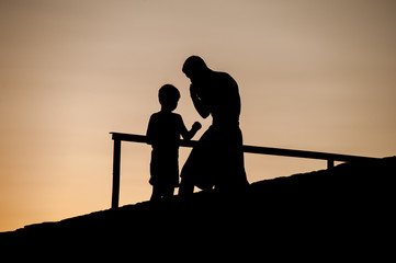 Fototapeta na wymiar Strong Young Tall Male Boxer Teaches His Little Son How To Properly Box