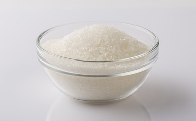 Glass bowl of sugar on white background