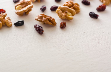 A variety of peeled walnuts and raisins on a white wooden background. View from above. Plenty of space for text.
