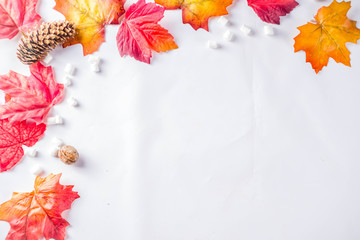 Autumn composition concept background. Cappuccino coffee or hot chocolate cup, with autumn bright leaves, pine cones, marshmallows. Flatlay on white background, simple top view pattern