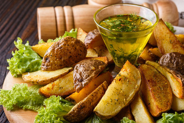 Potato wedges baked in their skins with lettuce on wooden background.