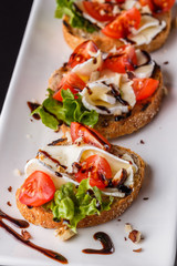 Bruschetta with tomatoes, lettuce, camambert, balsamic vinegar