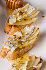 Appetizer bruschetta with pear, honey, walnut and blue cheese on white plate