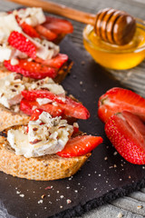 Bruschetta with strawberries, blue cheese, walnut and honey on stoyn plate