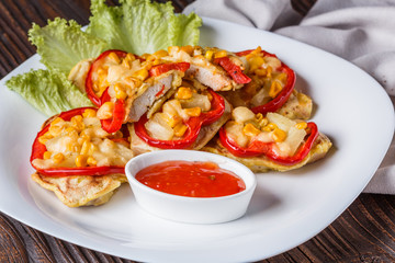 Chicken fillet in a batter with corn, paprika, lettuce and spicy tomato sauce on white plate