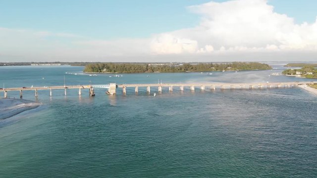 The strong blue currents of Longboat Pass sweep below the Longboat Key Pass bridge.  A recreational fishing hotspot.during the summer.  Jewfish Key is visible behind the bridge