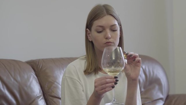 Sad woman holding wedding ring under the wine glass. Family problems. Betrayal, divorce, breakup concept. Restless girl having problems in personal life suffers break up, misunderstanding in family.