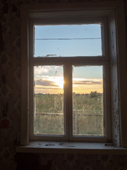view of summer sunset through old dirty window