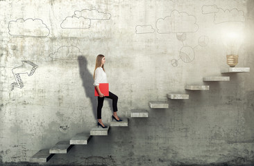 Side view of young businesswoman climbing the stairs with idea lamp on concrete background