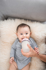 Young mother is feeding her baby at room