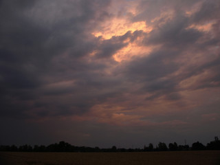 a colorful round storm cloud over a cereal field