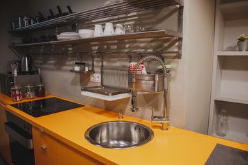 Modern kitchen interior, orange worktop, sink, stove, open shelving with dishes 1