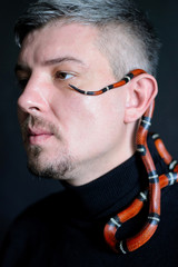 dark photo portrait of a man with a red snake