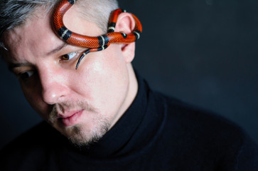 portrait of a mature man with a red snake a dark photo