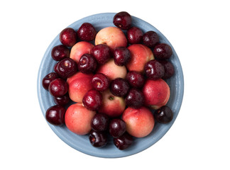 Sweet cherries and ripe juicy nectarines in a dish, on white background.